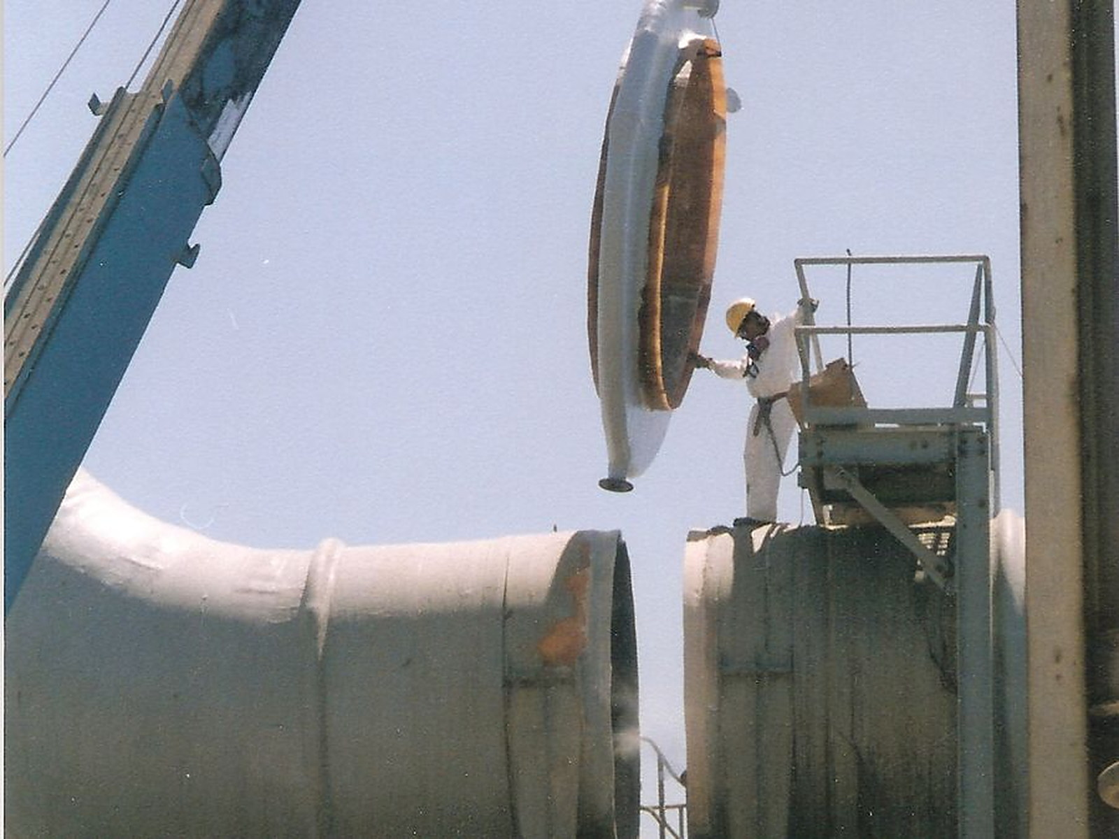 Large-diameter FRP expansion joint being lifted into a duct run on site